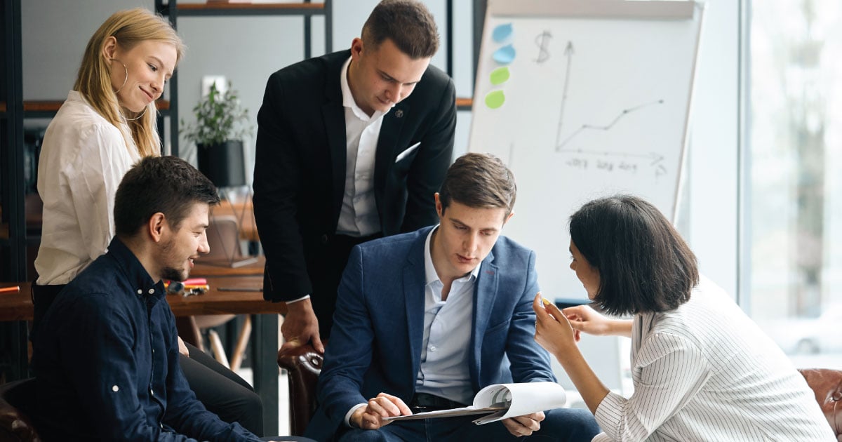 Leader of the company analyzing data surrounded by his team 